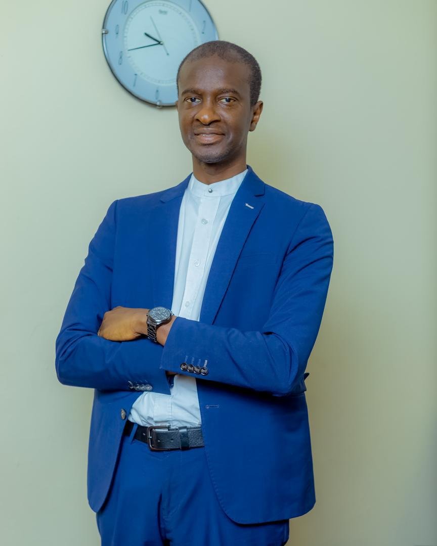 Malick H.B Jallow standing in a blue suit